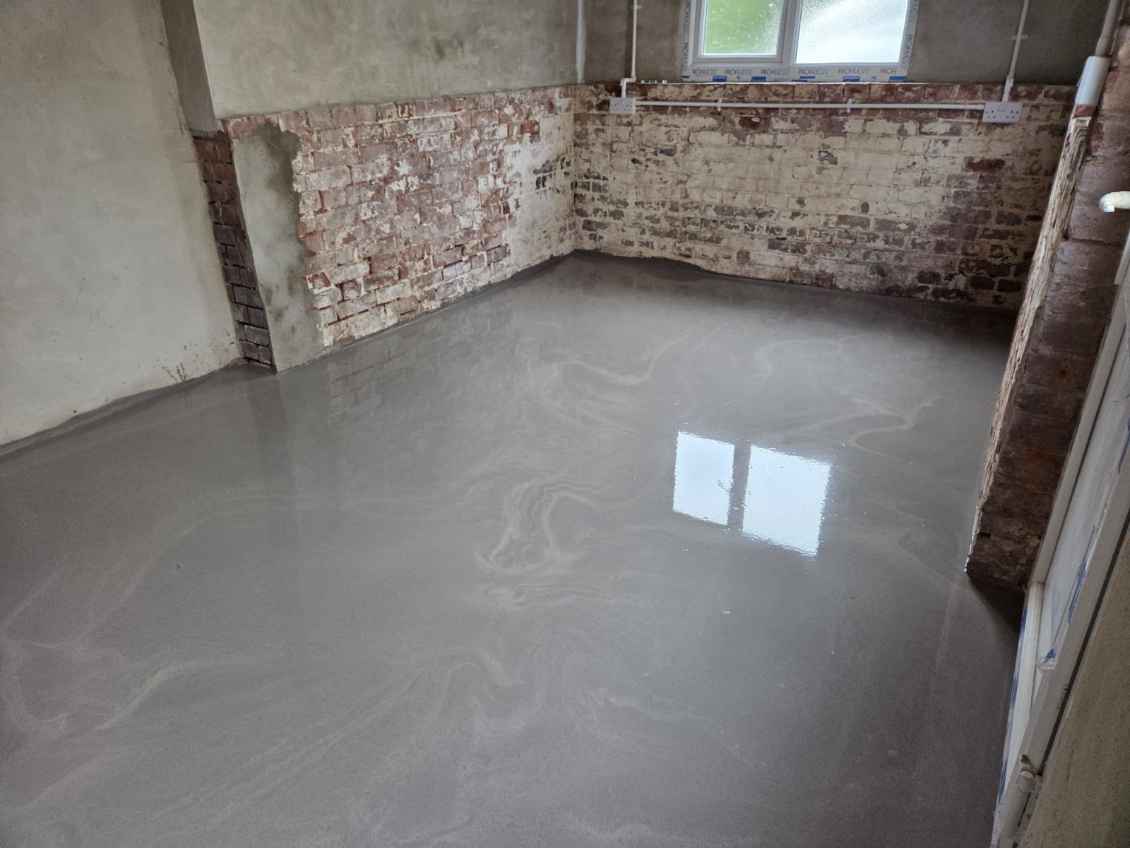New liquid screed floor with reflective finish in a stripped-back room